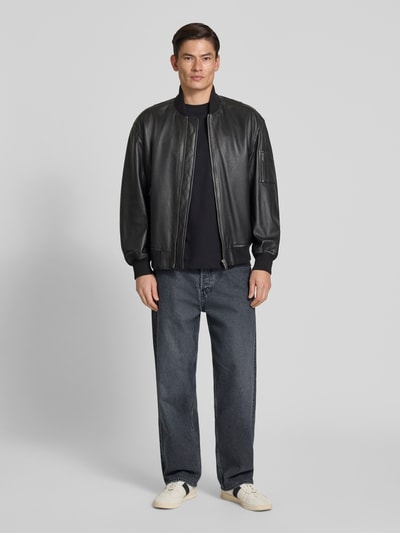 Männermodel trägt Loose Fit Baggy Jeans aus reiner Baumwolle Modell 'JAAMEO' von Armedangels in denimblauer Optik, 5-Pocket-Design, Ganzkörperansicht von vorne.