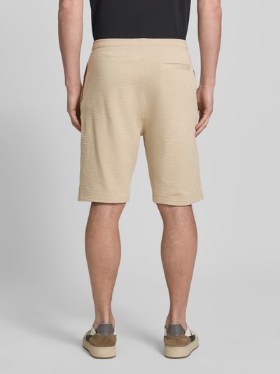 Männermodel trägt Relaxed Fit Bermudas aus Baumwoll-Mix Modell 'DETROIT' von s.Oliver RED LABEL, beige, Waffelstruktur, Rückansicht.