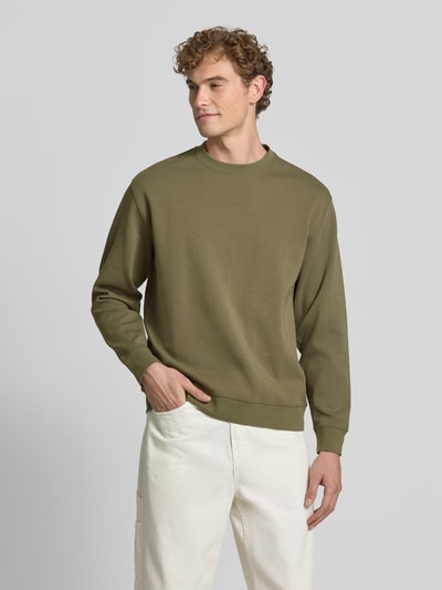 Mannenmodel draagt slim fit pullover uit pure katoen 'TOM' van Selected in olijfgroen met glad oppervlak, heren sweatshirt, frontaal totaalbeeld.