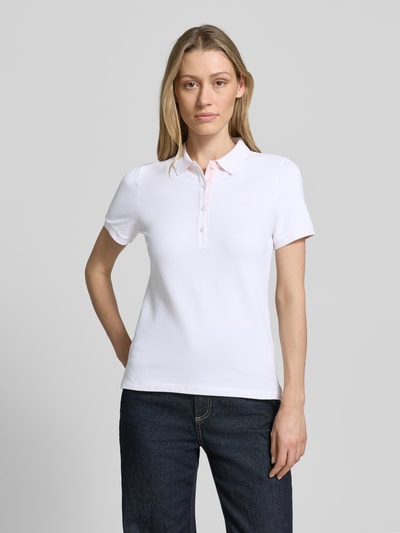 Frauenmodel trägt Slim Fit Poloshirt mit Label-Stitching von Gant aus Baumwoll-Elasthan-Mix mit Knopfleiste, Rückenlänge 59 cm, Ganzkörperansicht von vorne.