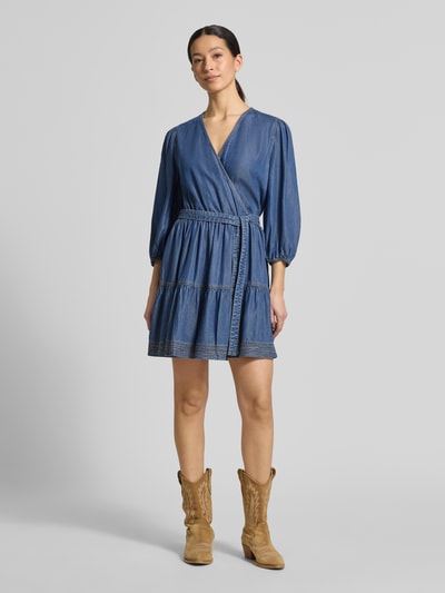 Modelka nosi tailliertes Freizeitkleid aus Lyocell Modell 'C_DARDY' von BOSS Orange w stylu jeansowym z kontrastowymi przeszyciami, mini, balonowe rękawy, elastyczny pasek w talii, widok całej sylwetki z przodu.
