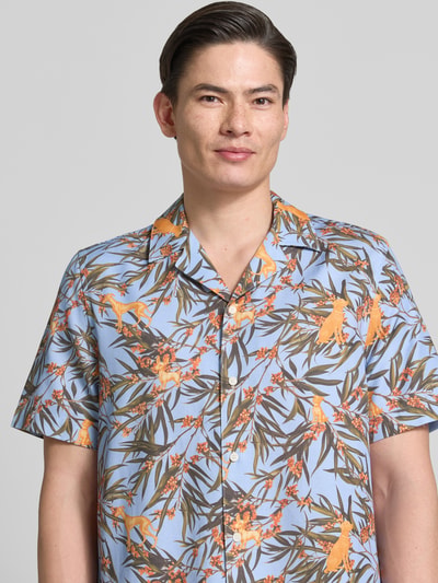 Männermodel trägt Relaxed Fit Freizeithemd aus Lyocell-Baumwoll-Mix von Armedangels, blau mit Allover-Muster und Resortkragen, Nahaufnahme Oberkörper.