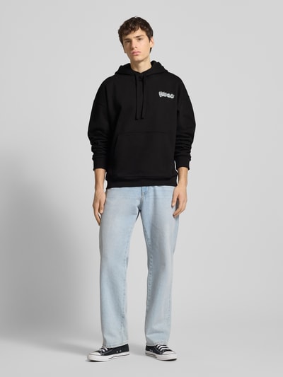 Männermodel trägt Relaxed Fit Hoodie aus reiner Baumwolle Modell 'NYROHOOD' von HUGO BLUE, Optik: Unifarben, Label-Print, Kängurutasche, Sweat, Ganzkörperansicht von vorne.