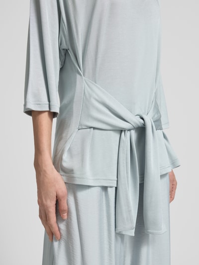 Frauenmodel trägt T-Shirt aus Viskose mit 3/4-Arm Modell 'SHARI' von GUIDO MARIA KRETSCHMER WOMAN in zartem Hellblau, Nahaufnahme Oberkörper. Reine Viskose, Relaxed-Fit, Rundhalsausschnitt, überschnittene Schultern, Rückenlänge 59 cm, Ärmellänge 28 cm.