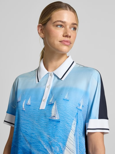 Frauenmodel trägt Regular Fit Bluse aus reinem Lyocell mit Polokragen von Marc Cain mit Allover-Motiv-Print in Blau, reines Lyocell, kurzärmeliges Design, Tunnelzug im Bund, Nahaufnahme Oberkörper.
