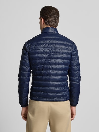 Männermodel trägt Regular Fit Jacke in Stepp-Optik Modell 'Sewall' von Blauer Usa in Dunkelblau, Rückenansicht, Ganzkörperansicht Rückansicht. Jacke aus glänzender Stepp-Optik, gefütterter Stehkragen, Zweiwege-Reißverschluss, Logo-Patch, Eingrifftaschen mit Reißverschluss, Rückenlänge 70 cm, Schulterbreite 44 cm, Brustweite 52 cm, Ärmellänge 64 cm, Herrenkontext.