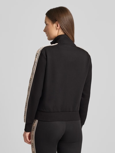 Frauenmodel trägt schwarze Regular Fit Sweatjacke mit Stehkragen Modell 'Britney' von Guess Activewear, Ganzkörperansicht Rückansicht.