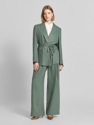 Frauenmodel trägt Anzugblazer mit Reverskragen von Jake*s Collection in Salbeigrün mit Stoffband und Paspeltaschen, Ganzkörperansicht von vorne.