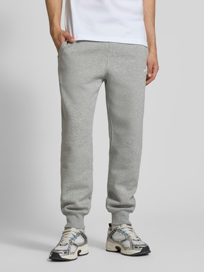 Männermodel trägt Sweatpants mit Label-Stitching und Gesäßtasche von Nike, grauer Baumwoll-Mix, Regular-Fit, Ganzkörperansicht von vorne.