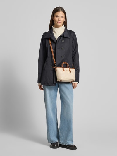Frauenmodel trägt Henkeltasche mit Logo-Applikation Modell 'MONOPLAY' von Tommy Hilfiger in Beige mit Allover-Muster, Kunstleder, Ganzkörperansicht von vorne