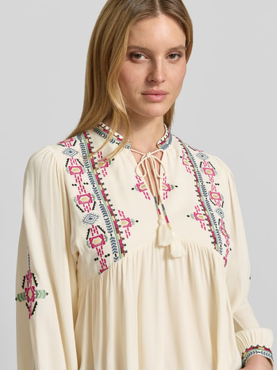 Frauenmodel trägt Tunikabluse mit Motiv-Stitching Modell 'TILT' von Bash in Creme mit bunten Stickereien aus reiner Viskose, Nahaufnahme Oberkörper.