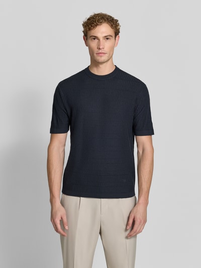 Männermodel trägt Slim Fit Strickshirt aus reiner Wolle von Emporio Armani in Dunkelblau, Kurzarm, gerippte Abschlüsse, Ganzkörperansicht von vorne.