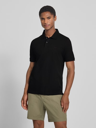 Männermodel trägt schwarzes Regular Fit Poloshirt aus reiner Baumwolle von s.Oliver RED LABEL, glatte Textur, Ganzkörperansicht von vorne.
