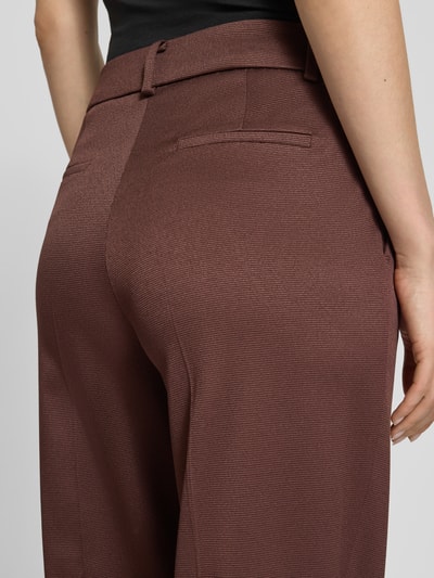 Frauenmodel trägt Wide Fit Stoffhose mit Viskose-Anteil von More & More in Braun mit Strukturmuster und Haken-Reißverschluss, Detailaufnahme Rückansicht. Elastischer-Material-Mix mit Viskose-Mix, Wide-Fit, Bügelfalten, Bundweite bei Größe 36: 37 cm, Innenbeinlänge bei Größe 36: 80 cm.