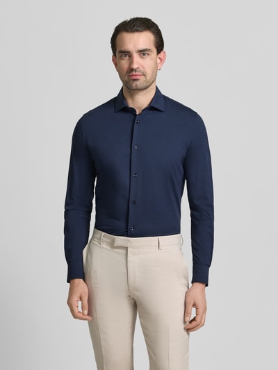 Męski model nosi Slim Fit Business-Hemd mit Knopfleiste von CRUNA, granatowy, krój slim fit, materiał z domieszką stretchu, koszula z kołnierzykiem kent, długość tyłu w rozmiarze 50: 65 cm, szerokość ramion w rozmiarze 50: 43 cm, długość rękawów w rozmiarze 50: 65 cm, widok całej sylwetki z przodu