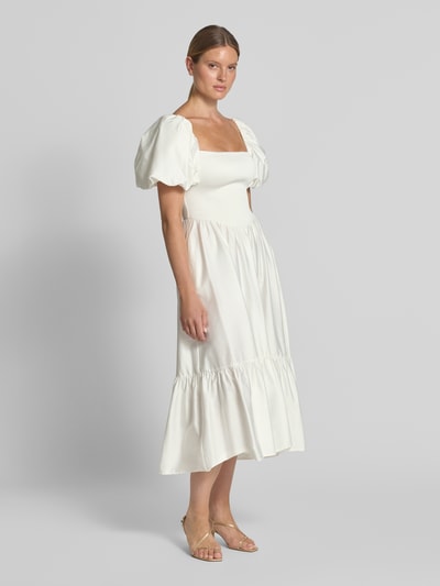 Frauenmodel trägt Cocktailkleid mit Smok-Details und Puffärmeln von Jake*s Cocktail, reine Baumwolle, cremefarben, A-Linie, Ganzkörperansicht von vorne.