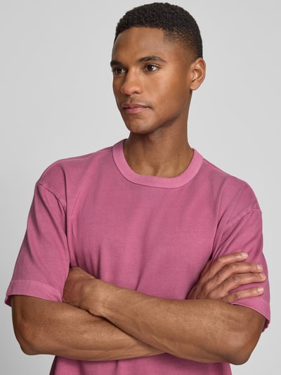 Männermodel trägt Cropped T-Shirt mit Rundhalsausschnitt von GAP, reine Baumwolle, Farbe Rosa, Nahaufnahme Oberkörper.