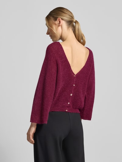 Frauenmodel trägt Relaxed Fit Cardigan mit Mohair-Alpaka-Anteil Modell 'Isaac' von ba&sh in Strick-Optik, 3/4-Arm, bordeauxrot, Ganzkörperansicht Rückansicht.