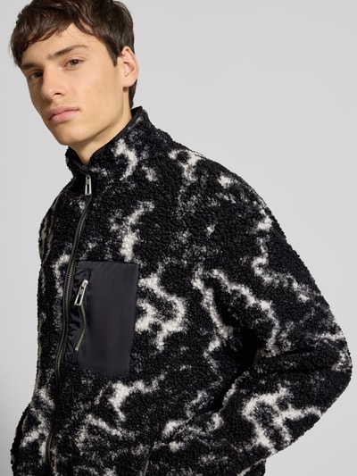 Męski model nosi Regular Fit Futerko-Kurtka z wzorem na całej powierzchni Model 'JAIMY' od Only & Sons, stójka, zamek błyskawiczny, długi rękaw, lamówka, tunel, kieszeń na piersi, imitacja futerka; kolor czarny z białym wzorem, faktura miękka; ujęcie: zbliżenie na górę ciała z przodu.
