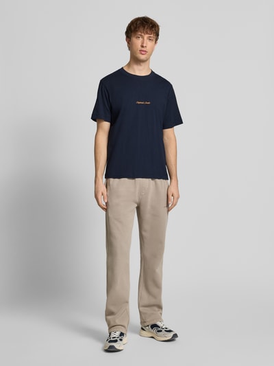 Männermodel trägt dunkelblaues T-Shirt mit Label-Stitching Modell 'NORREBRO' von Jack & Jones, regular Fit, Ganzkörperansicht von vorne.