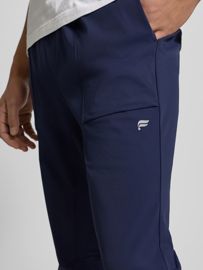 Männermodel trägt Slim Fit Jogger mit elastischem Bund von Fabletics, Elastischer-Material-Mix, Eingrifftaschen, Nahaufnahme Oberschenkel.