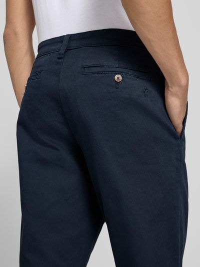 Männermodel trägt Straight Fit broek uit katoenmix van REVIEW in donkerblauw met steekzakken en achterzak, detailopname rugaanzicht. Context: Heren broek van REVIEW, elastische katoenmix, straight fit, steekzakken, achterzakken, knoop- en ritssluiting, bandwijdte bij maat M: 42 cm, binnenbeenlengte bij maat M: 69 cm.