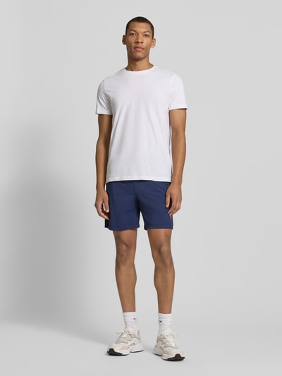 Mężczyzna nosi Regular Fit Shorts mit Logo-Print von Fabletics, elastyczny materiał, krój regular fit, szerokość w rozmiarze M: 39 cm, widok całej sylwetki z przodu.