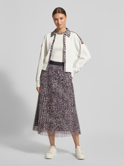 Vrouwenmodel draagt Midirok in plooien-look met all-over dierenprint van Marc Cain, lichte A-lijn, elastische band, gestikt logo, bandwijdte bij maat 36 38 cm, totale lengte 86 cm, Ganzkörperansicht von vorne.