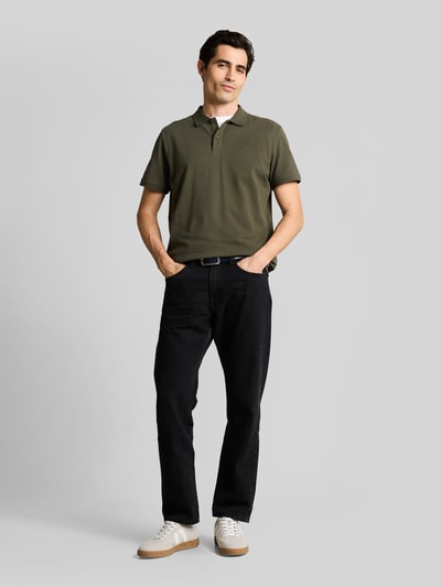 Männermodel trägt Regular Fit Poloshirt aus reiner Baumwolle von Tom Tailor in Optik: Unifarben, Piqué-Struktur und Logo-Stitching, Ganzkörperansicht von vorne.