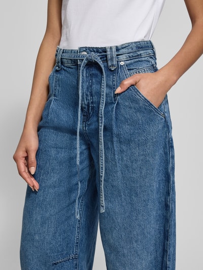 Frauenmodel trägt Wide Leg Jeans aus Baumwoll-Lyocell-Mix Modell 'C_PLEATED BARREL 1.0' von BOSS Orange in Denim-Optik, Nahaufnahme Oberkörper.