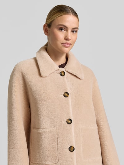 Frauenmodel trägt Regular Fit Jacke aus reiner Wolle von OAKWOOD in Beige mit Umlegekragen und großen Knöpfen, Nahaufnahme Oberkörper.