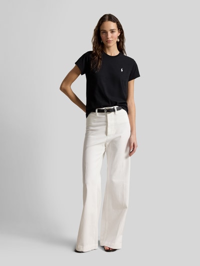 Frauenmodel trägt Regular Fit T-Shirt aus reiner Baumwolle von Polo Ralph Lauren in Schwarz, kombiniert mit weißer Hose, Ganzkörperansicht von vorne. Damen T-Shirt von Polo Ralph Lauren.