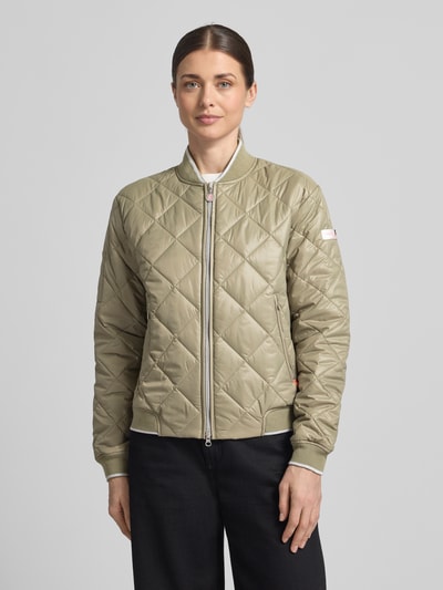 Modelka kobieca ma na sobie Steppjacke mit Zweiwege-Reißverschluss Modell 'BOY' od Frieda & Freddies w kolorze beżowym, krój regular fit, stójka, kieszenie na zamek, długość tyłu w rozmiarze 36: 20 cm, szerokość ramion w rozmiarze 36: 16 cm, szerokość w rozmiarze 36: 21 cm, długość rękawa w rozmiarze 36: 24 cm, pikowana faktura, widok całej sylwetki z przodu.