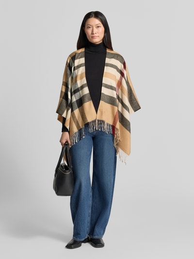 Frauenmodel trägt Relaxed Fit Poncho in Strick-Optik von FRAAS, beige mit gestreiftem Muster, Fransen-Abschluss, 3/4-Arm, Ganzkörperansicht von vorne.