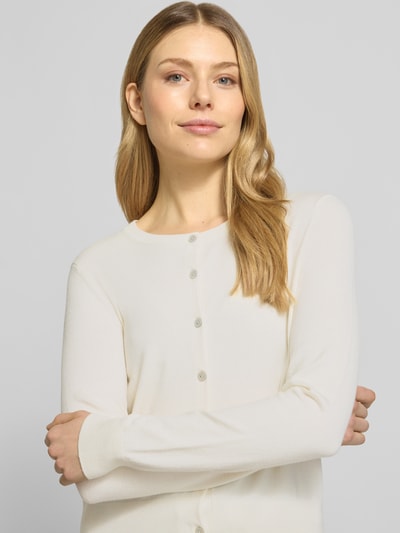 Kobiece modelka nosi Regular Fit Cardigan aus Viskose-Mix von Christian Berg Woman, okrągły dekolt, listwa guzikowa, długość tyłu 48 cm, długość rękawów 62 cm; mieszanka wiskozy, krój regular fit, kolor jasny, delikatna tekstura; zbliżenie na górną część ciała, widok z przodu.