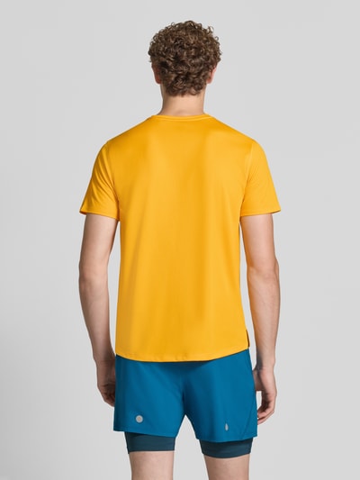 Męski model trägt t-shirt z nadrukiem z logo Model 'CORE' od ASICS TIGER w prostym kroju i okrągłym dekolcie, Długość tyłu w rozmiarze M: 72 cm, kolor żółty, widok całej sylwetki z tyłu.
