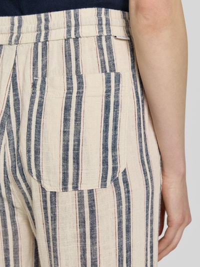 Vrouwenmodel draagt Wide Leg Pants aus Viskose-Mix mit Kordelzug Modell 'LACEY' van Mustang, mix van linnen en viscose, beige met blauw en rood gestreept, steekzakken en achterzak, bandwijdte maat 36: 40 cm, binnenbeenlengte 80 cm, detailopname heup.