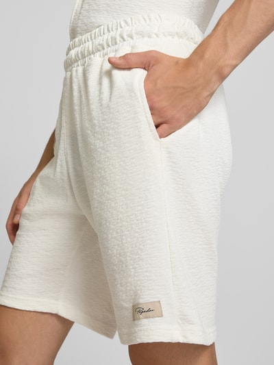 Männermodel trägt Shorts mit Label-Detail und elastischem Bund Modell 'Arcos' von PEGADOR in Weiß, strukturierte Oberfläche, Nahaufnahme Oberschenkel. Baumwolle, Regular Fit, Bundweite 38 cm, Innenbeinlänge 24 cm.
