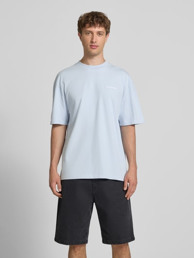 Männermodel trägt Oversized T-Shirt mit Label-Stitching von Pegador aus Baumwoll-Mix, Rundhalsausschnitt, hellblau, Rückenlänge 70 cm, Ganzkörperansicht von vorne.