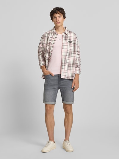 Męski model nosi Regular Fit Jeansshorts aus Baumwoll-Mix Model 'PLY' von Only & Sons, stylizowana na denim, aplikacja: naszywka z logo, szlufki na pasek, zakończenie nogawek: nogawka z mankietem, 5 kieszeni, materiał: mieszanka bawełny; jasnoszary kolor, gładka faktura, prostokątne kształty; Ganzkörperansicht von vorne.