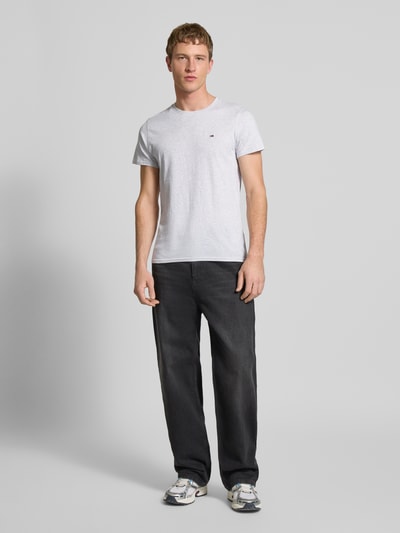 Männermodel trägt Regular Fit T-Shirt aus reiner Baumwolle von Tommy Jeans, Optik: Unifarben, Logo-Stitching, Ganzkörperansicht von vorne.