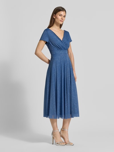 Kobiece modelka nosi Sukienka koktajlowa 'Schimmerndes Cocktailkleid mit V-Ausschnitt' od Vera Mont, efekt błyszczący, Tiul, linia A, sukienka midi, dekolt w serek, długość tyłu w rozmiarze 36: 100 cm, szerokość w rozmiarze 36: 42 cm, widok całej sylwetki z przodu.