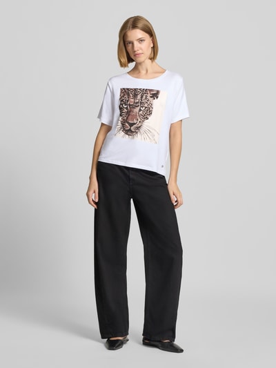 Frauenmodel trägt T-Shirt mit Motiv-Print und Ziersteinbesatz von monari, Weiß mit Leoparden-Print, Regular Fit, Ganzkörperansicht von vorne.