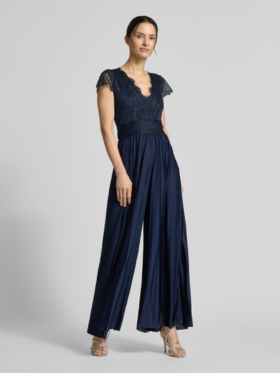 Modelka kobieca nosi ciemnogranatowy Abendkleid mit Spitzenbesatz Modell 'Emelie' od GUIDO MARIA KRETSCHMER WOMAN, krój taliowany, dekolt V, długość całkowita 148 cm, Szerokość w rozmiarze 36: 33 cm, tkanina z koronką, gładka tekstura. Ganzkörperansicht von vorne.