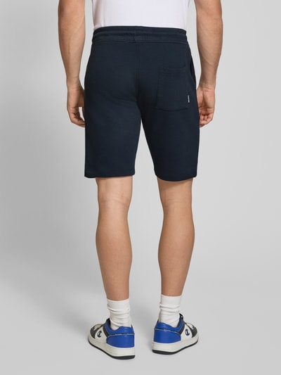Männermodel trägt Straight Fit Shorts mit Logo-Stitching Modell 'Fillip' von Blend, Reine Baumwolle, Strukturmuster, Ganzkörperansicht Rückansicht.