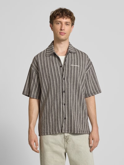 Männermodel trägt Relaxed Fit Freizeithemd mit Label-Stitching Modell 'Forno' von Pegador, Allover-Look, Reine Baumwolle, Kentkragen, Knopfleiste, Ganzkörperansicht von vorne.