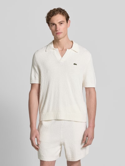 Männermodel trägt Regular Fit Poloshirt aus Baumwoll-Mix von Lacoste, Optik: Unifarben, Bouclé-Textur, Label-Patch, Ganzkörperansicht von vorne.