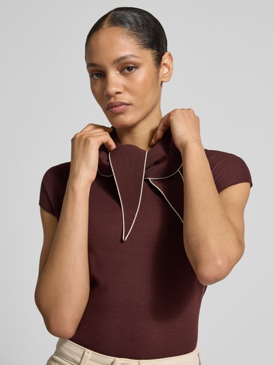 Frauenmodel trägt Blusenshirt aus Viskose-Mix mit V-Ausschnitt Modell 'BERT' von Mango in bordeaux, glatte Textur, Nahaufnahme Oberkörper. Damen Blusenshirt im Allover-Look, Regular Fit, Rückenlänge bei Größe S: 54 cm.