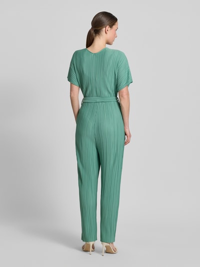 Vrouwenmodel draagt Jumpsuit met plissévouwen en strikceintuur model 'Pe44arl' van ZABAIONE in groen, getailleerd model, totale lengte 145 cm, ruglengte 38 cm, borstwijdte 39 cm, binnenbeenlengte 69 cm, wikkellook, V-hals, plissévouwen, strikceintuur, all-over look, driekwartmouwen, elegante textuur, achteraanzicht volledige lichaamsopname.