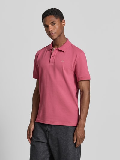 Männermodel trägt Regular Fit Poloshirt aus reiner Baumwolle von Tom Tailor in Dunkelrosa, glatte Struktur, Ganzkörperansicht von vorne.